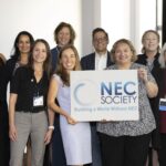 Staff grouped together holding NEC Society sign